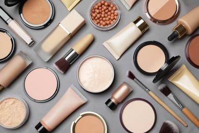 Face powders and other makeup products on grey background, flat lay