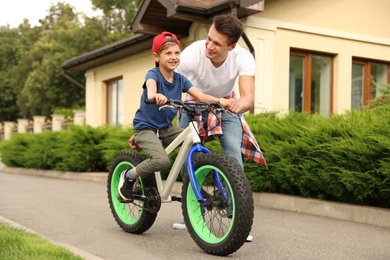 Dad teaching son to ride bicycle outdoors