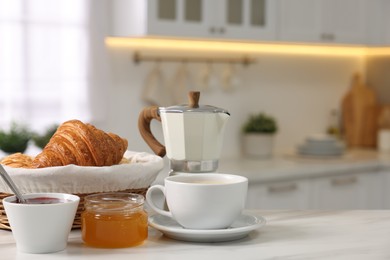 Photo of Breakfast served in kitchen. Fresh croissants, jam, honey and coffee on white table, space for text