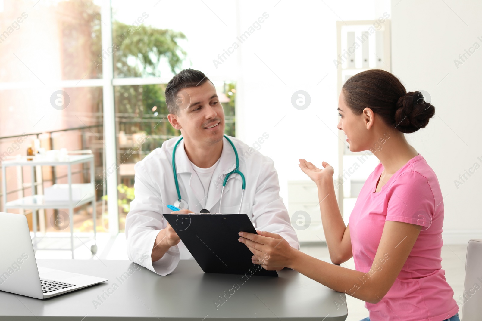 Photo of Young doctor listening to patient's complaints in hospital