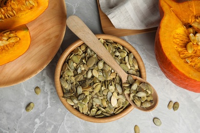 Photo of Flat lay composition with raw pumpkin seeds on light grey marble table