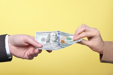 Photo of Man giving money to woman on yellow background, closeup. Currency exchange
