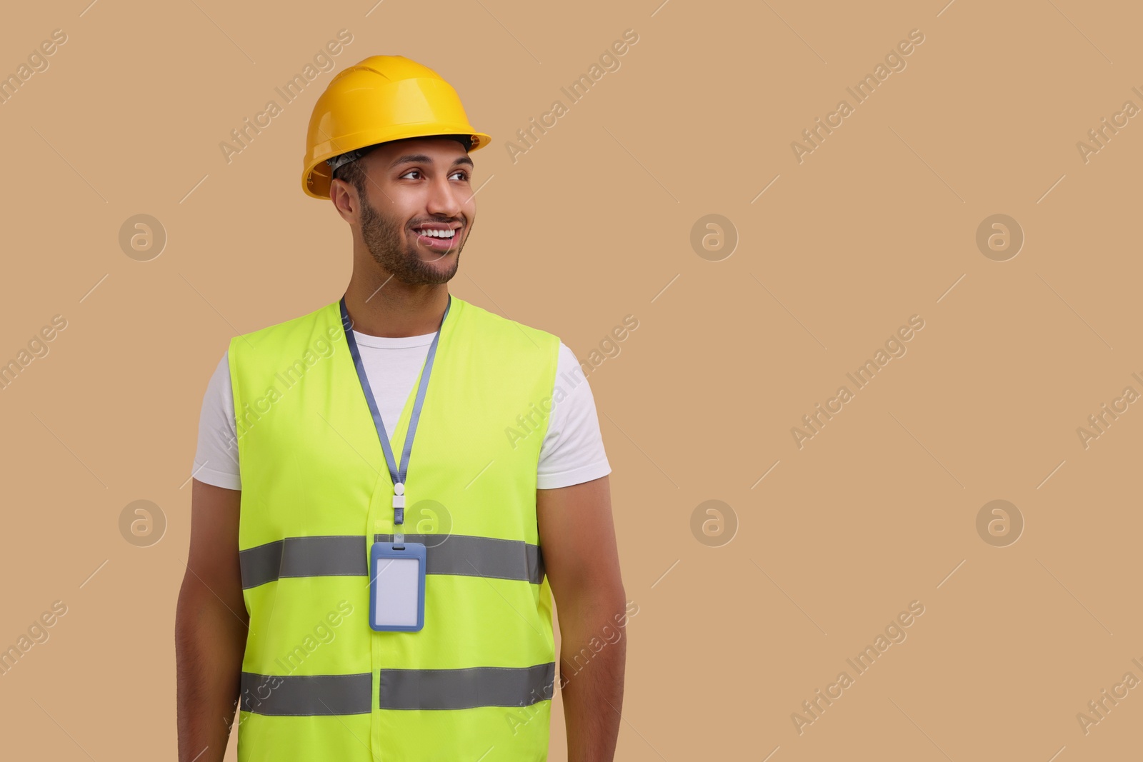 Photo of Engineer with hard hat and badge on beige background, space for text