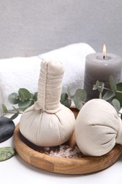 Photo of Spa composition with herbal massage bags and eucalyptus branches on white table