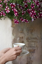 Photo of Young woman with cup of delicious coffee outdoors