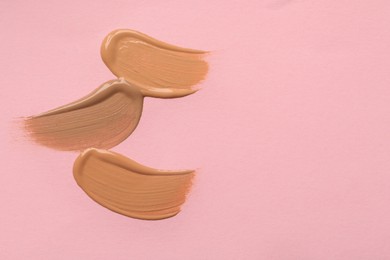 Photo of Samples of liquid skin foundation on pink background, top view. Space for text