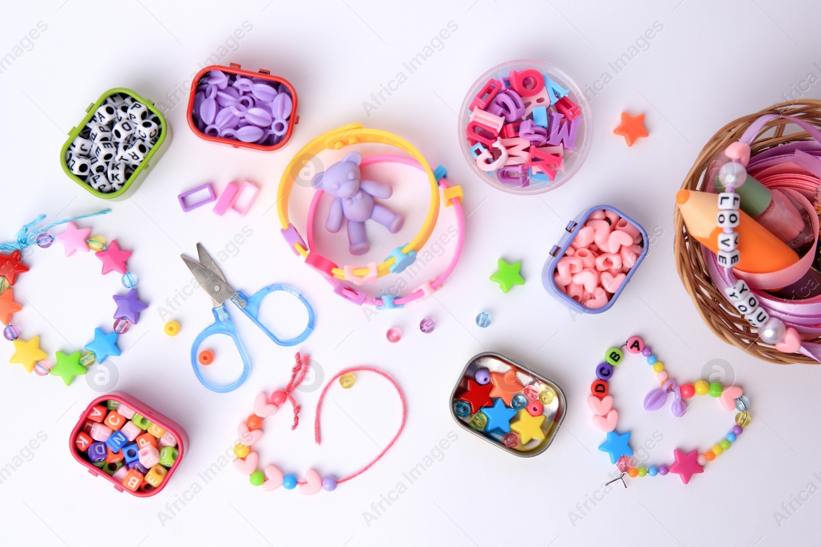 Photo of Kid's handmade beaded jewelry and different supplies on white background, top view