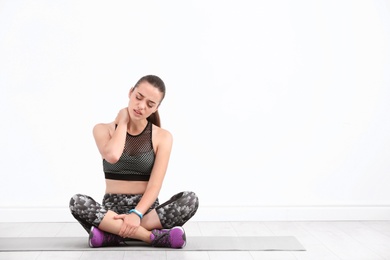 Photo of Female athlete suffering from neck pain during training indoors