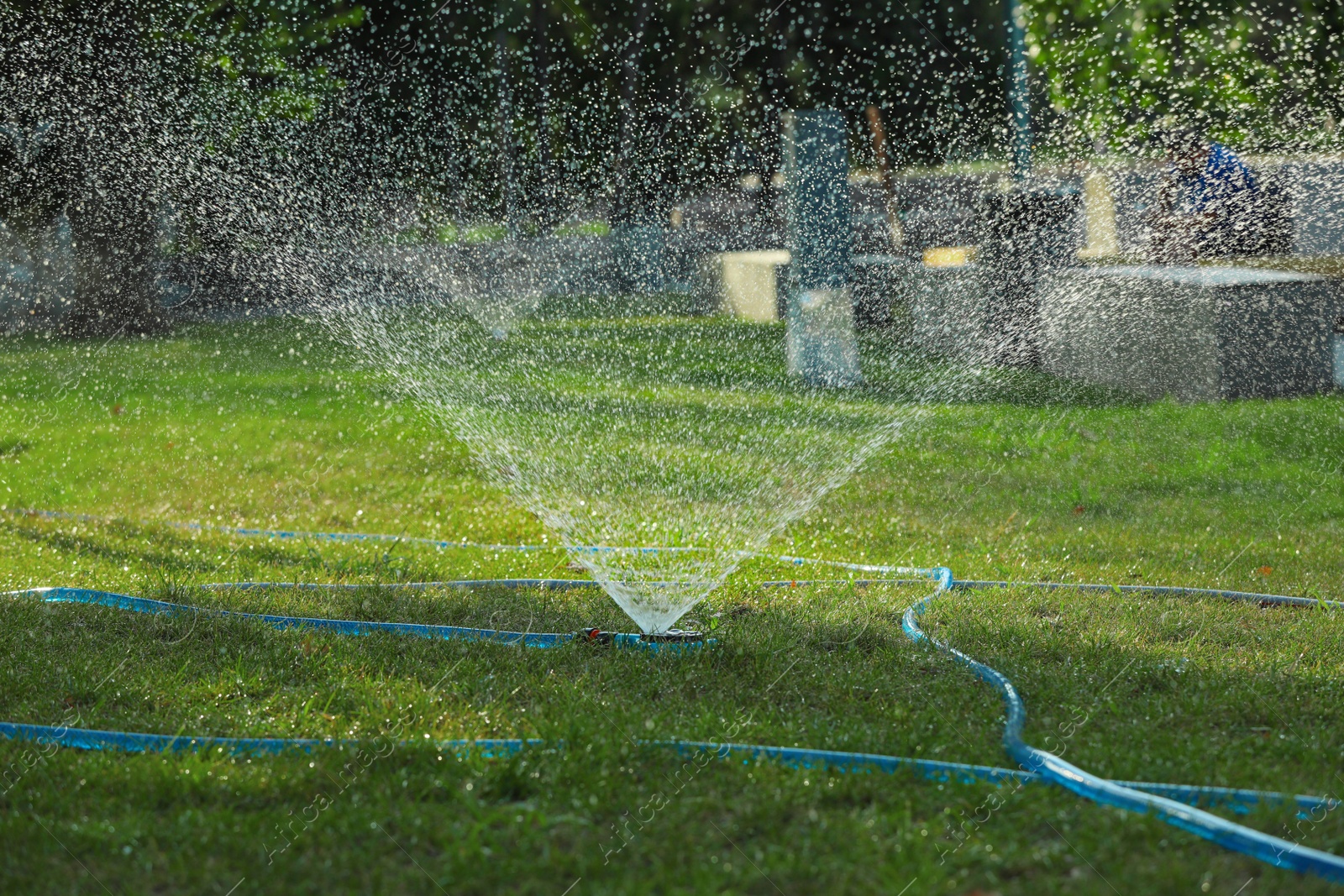 Photo of Automatic sprinkler watering green grass in park. Irrigation system