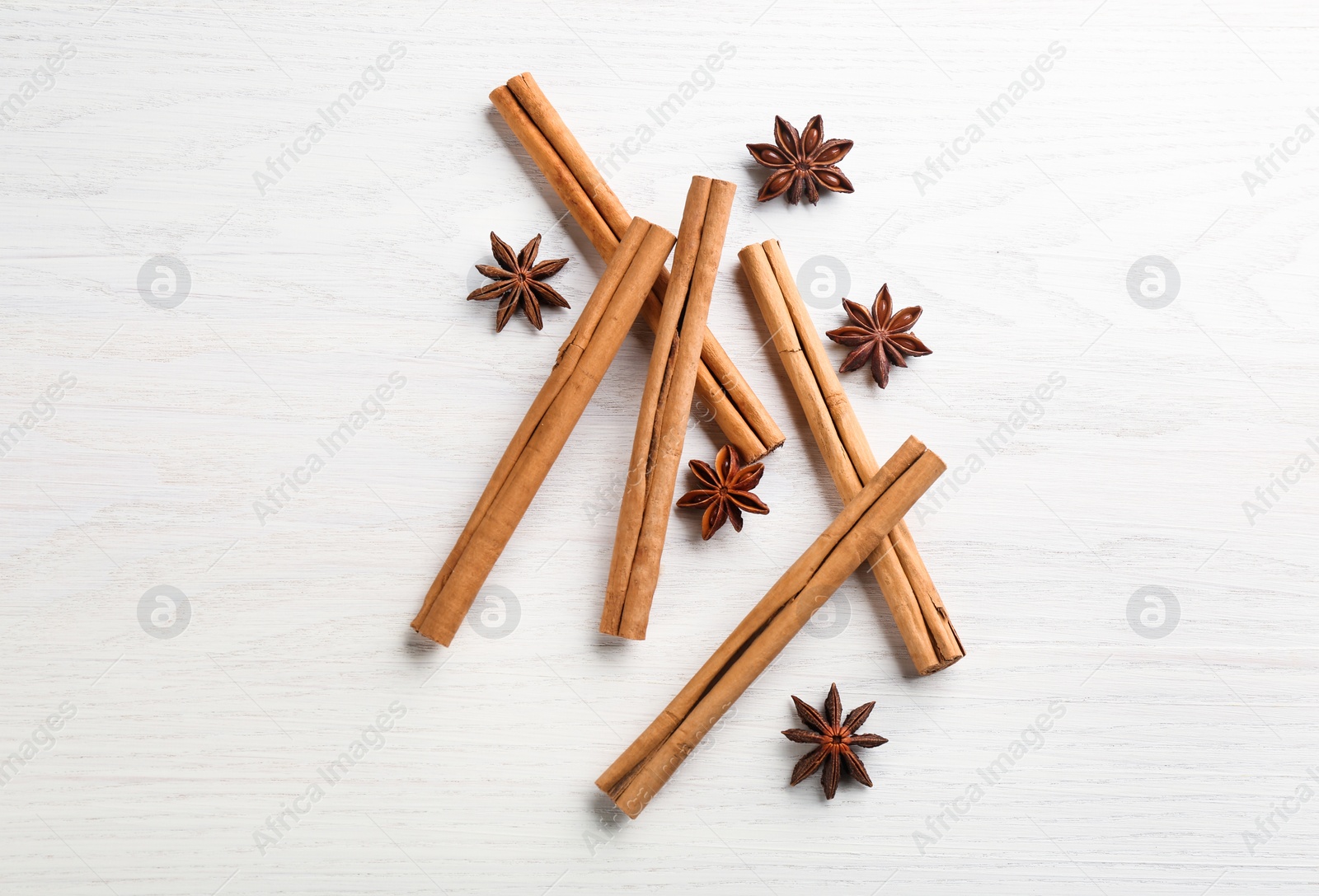 Photo of Aromatic cinnamon sticks and anise on white wooden table, flat lay