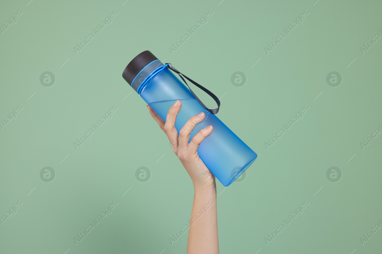 Photo of Woman holding bottle of water on green background, closeup