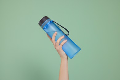 Woman holding bottle of water on green background, closeup