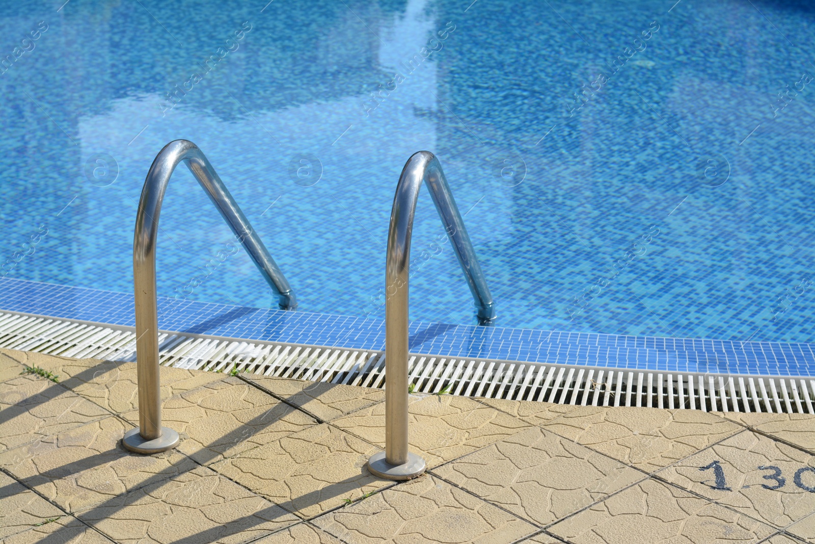 Photo of Outdoor swimming pool with ladder and handrails on sunny day