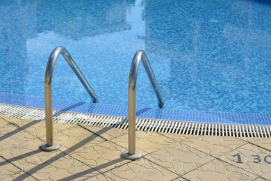 Photo of Outdoor swimming pool with ladder and handrails on sunny day