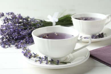 Photo of Fresh delicious tea with lavender and beautiful flowers on white wooden table