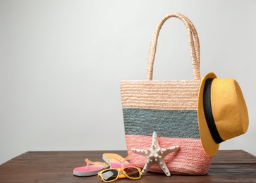 Bag with beach objects on table against light background