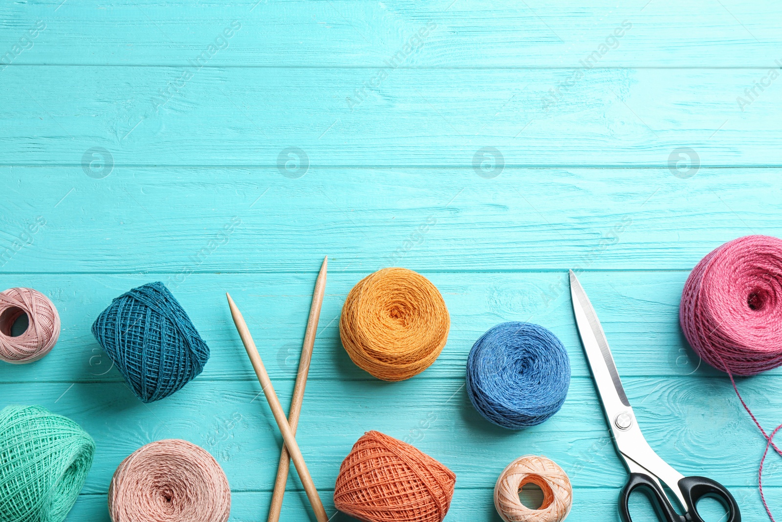 Photo of Flat lay composition with colorful clews of threads on wooden table, space for text