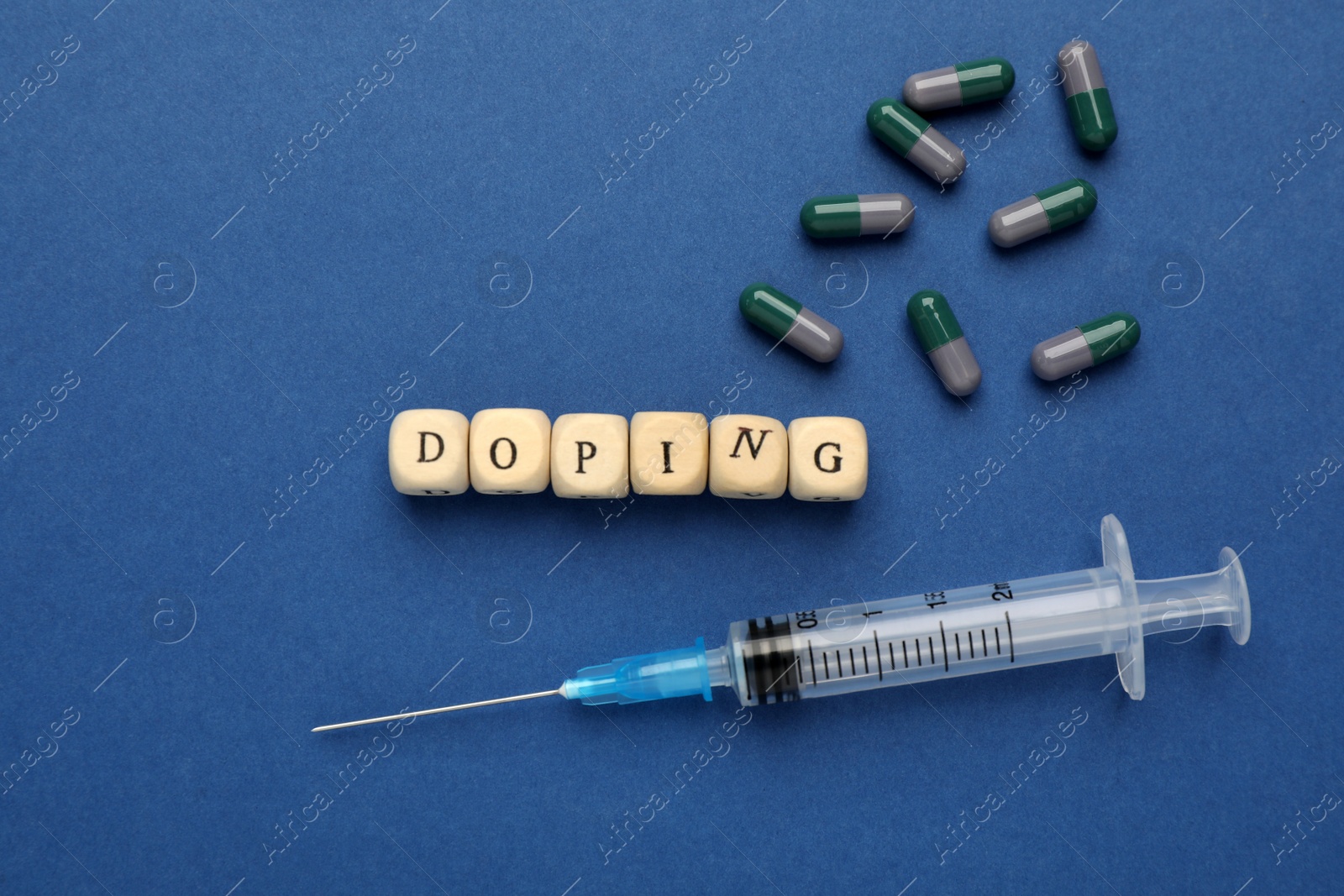 Photo of Wooden cubes with word Doping and drugs on blue background, flat lay