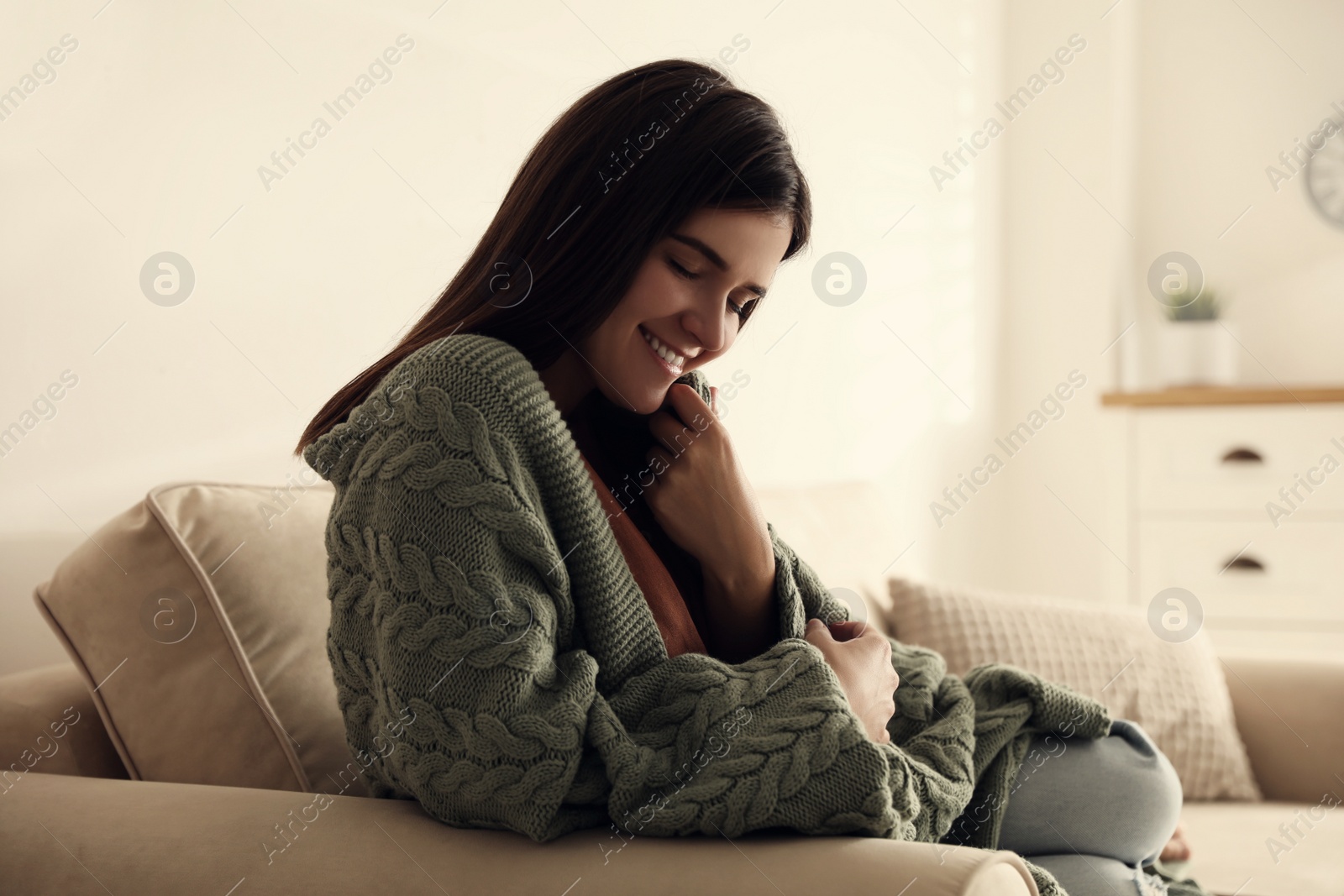 Photo of Woman covered with warm green plaid sitting on sofa at home