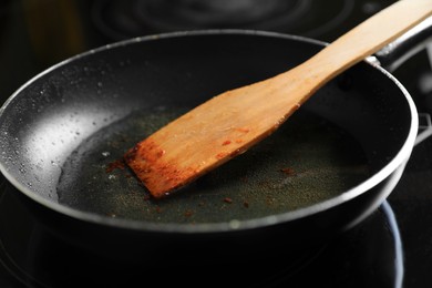 Frying pan with spatula and used cooking oil on stove, closeup