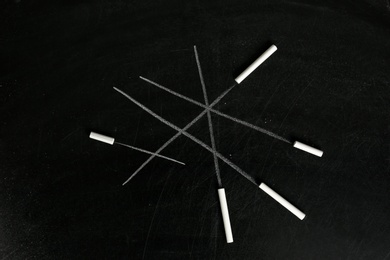 Photo of Chalk sticks on blackboard, closeup. School equipment