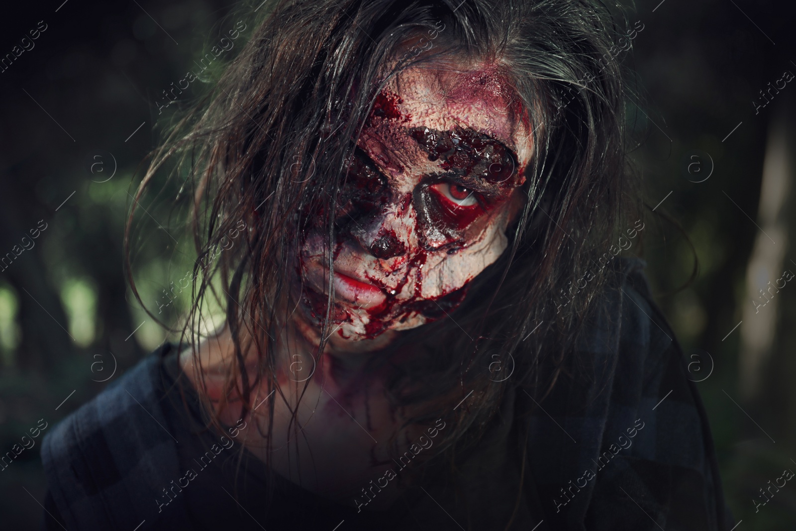 Photo of Scary zombie with bloody face outdoors, closeup. Halloween monster