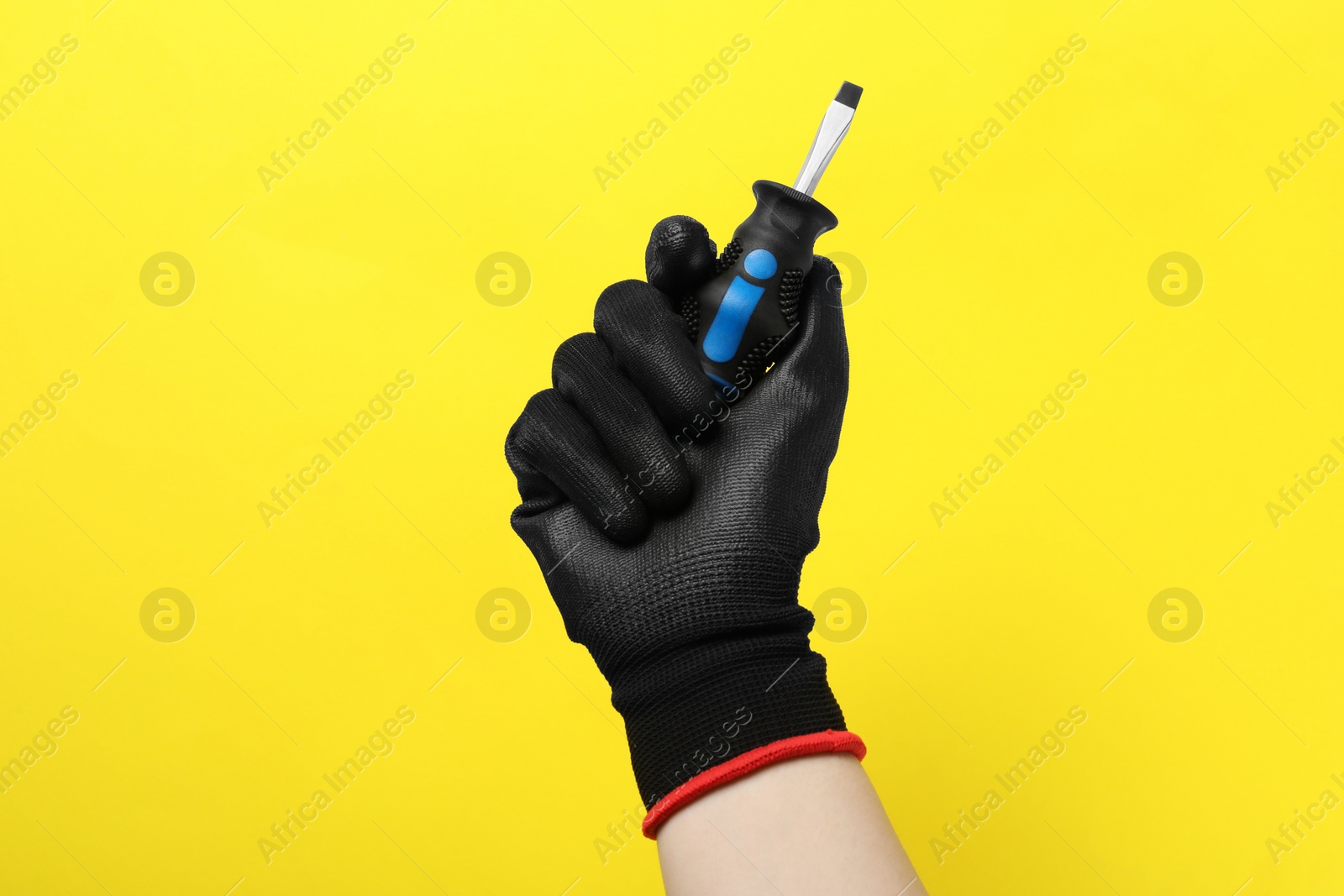 Photo of Woman holding small screwdriver on yellow background, closeup