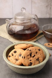 Photo of Delicious chocolate chip cookies and tea on grey table