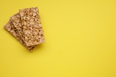 Tasty peanut bars (kozinaki) on yellow background, flat lay. Space for text