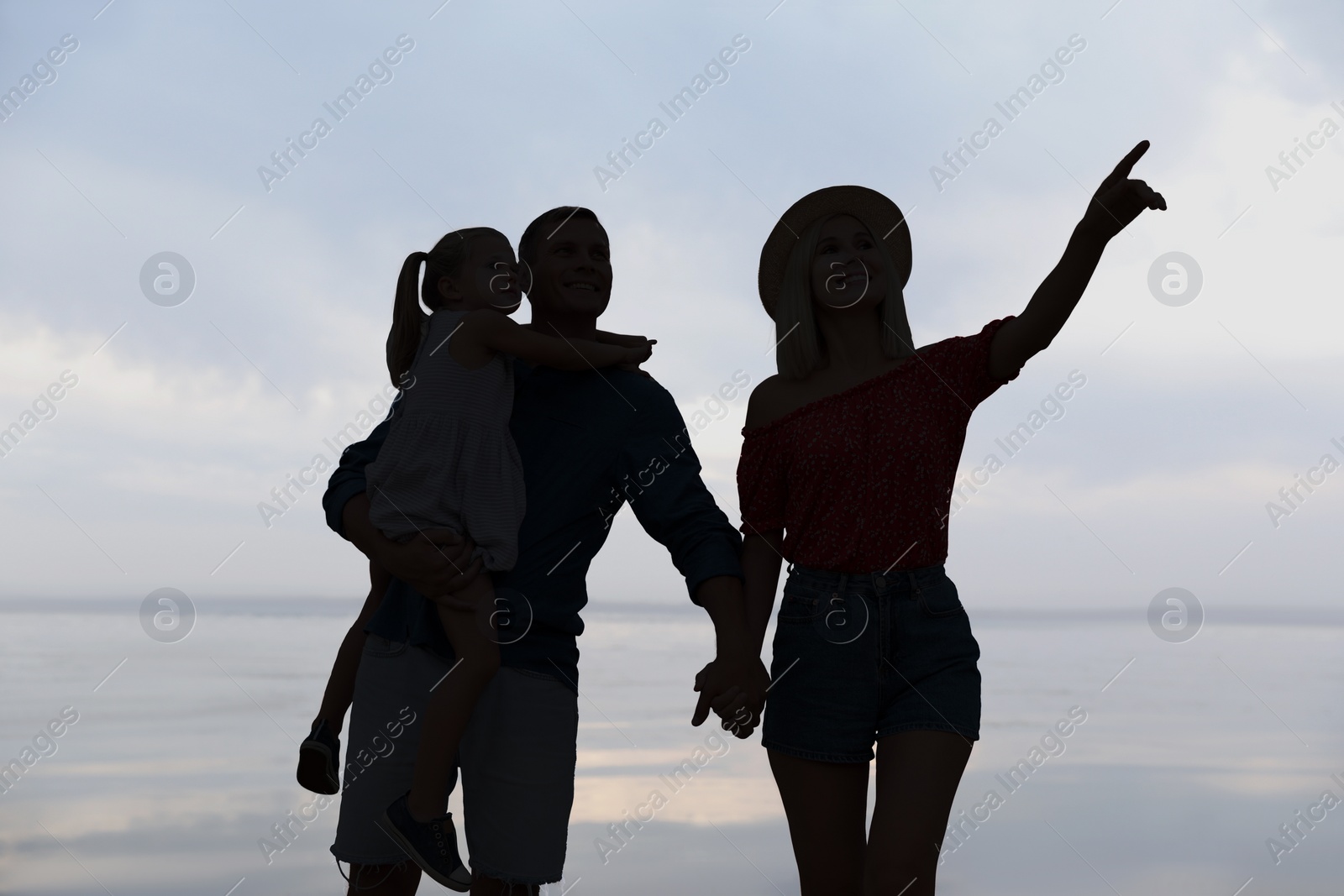 Image of Silhouette of family. Parents with child walking near sea