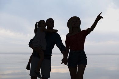 Image of Silhouette of family. Parents with child walking near sea