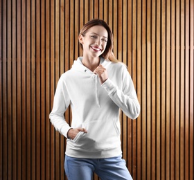 Photo of Portrait of woman in hoodie sweater on wooden background. Space for design