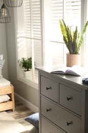 Photo of Grey chest of drawers near window in stylish room interior