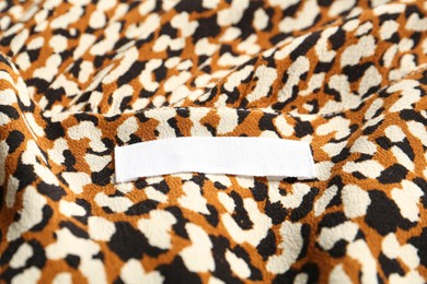 Photo of Blank clothing label on stylish apparel, closeup