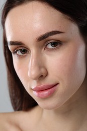 Beautiful young woman with healthy skin on light grey background, closeup