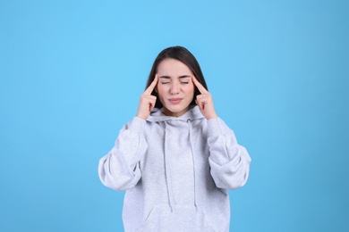 Portrait of stressed young woman on light blue background