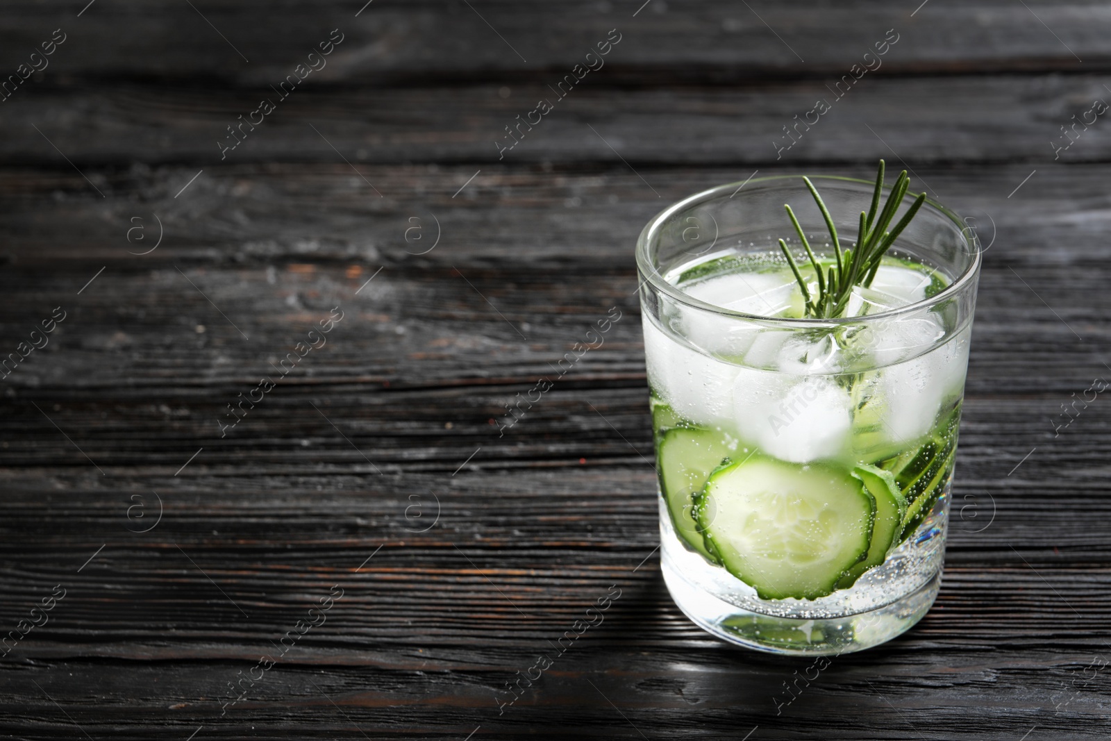 Photo of Glass of fresh cucumber water on wooden table. Space for text