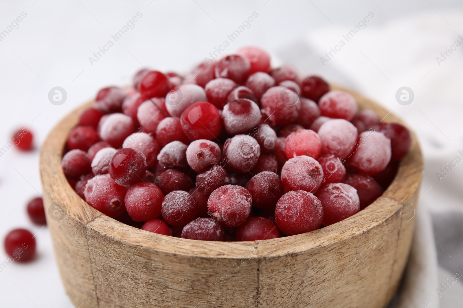 Photo of Frozen red cranberries in bowl on table, closeup