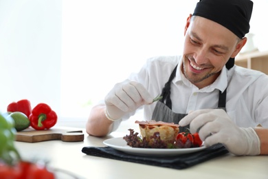 Professional chef presenting dish on table in kitchen