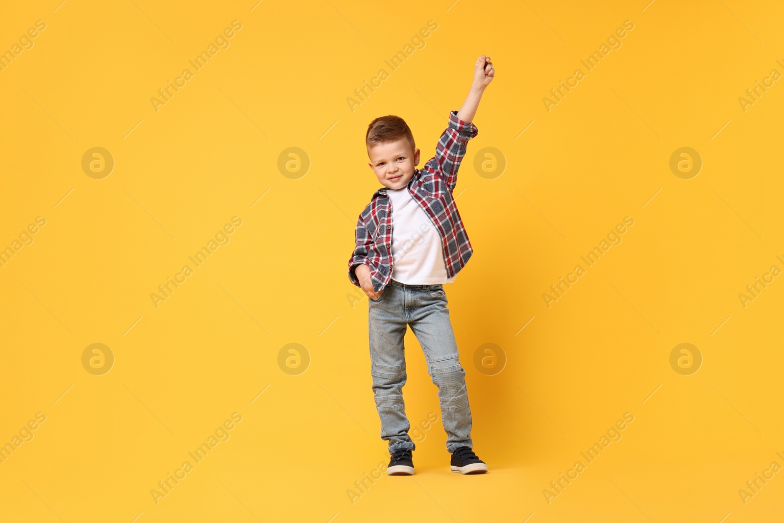 Photo of Happy little boy dancing on yellow background