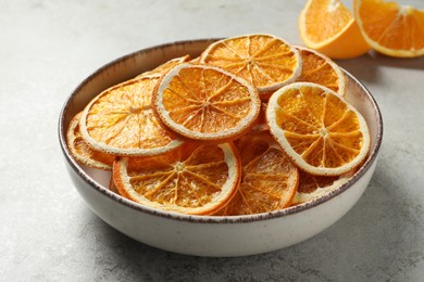 Photo of Bowl of dry orange slices on light table, closeup