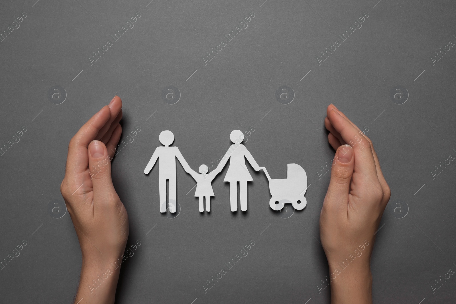Photo of Woman protecting paper family figures on grey background, top view. Insurance concept