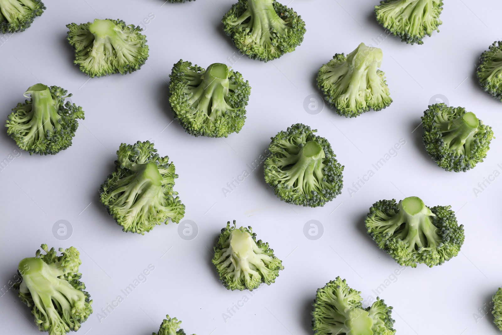 Photo of Many fresh green broccoli pieces on white background, above view