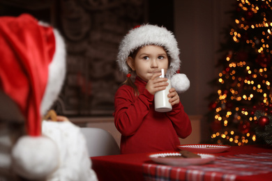 Cute little child with glass of milk at table in dining room. Christmas time