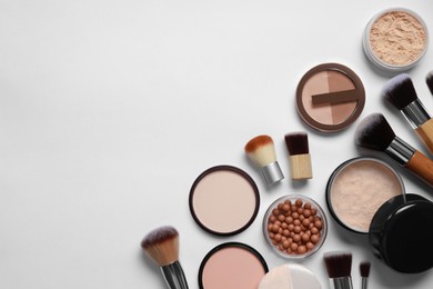 Different face powders and makeup brushes on light background, flat lay. Space for text