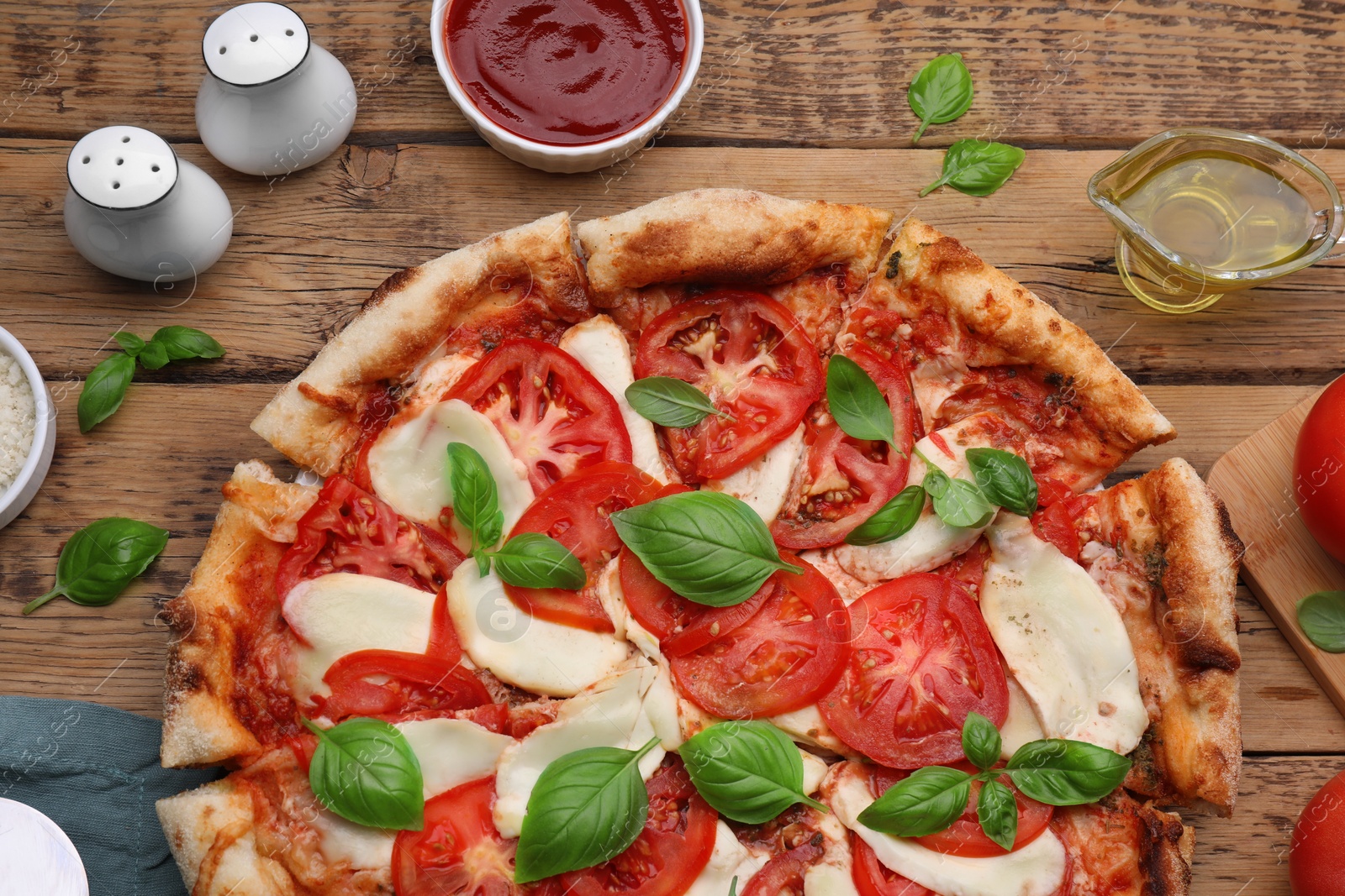 Photo of Delicious Caprese pizza and ingredients on wooden table, flat lay