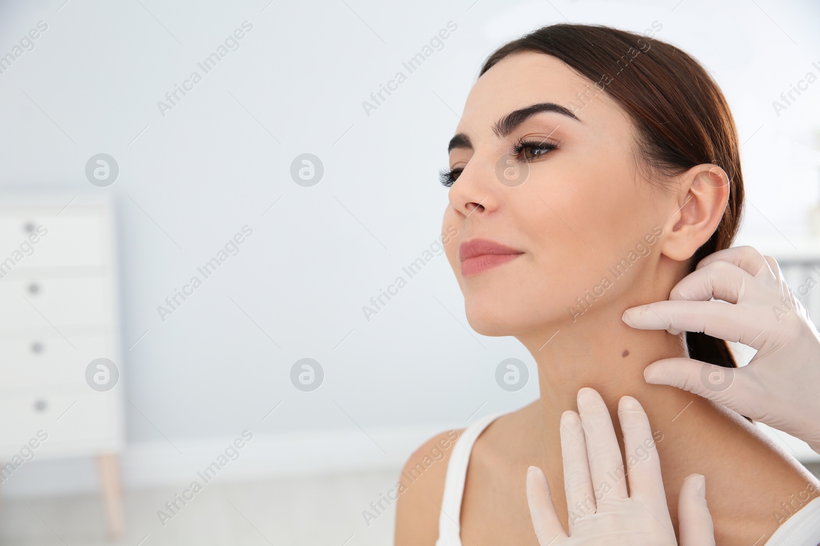 Photo of Dermatologist examining young patient's birthmark in clinic. Space for text