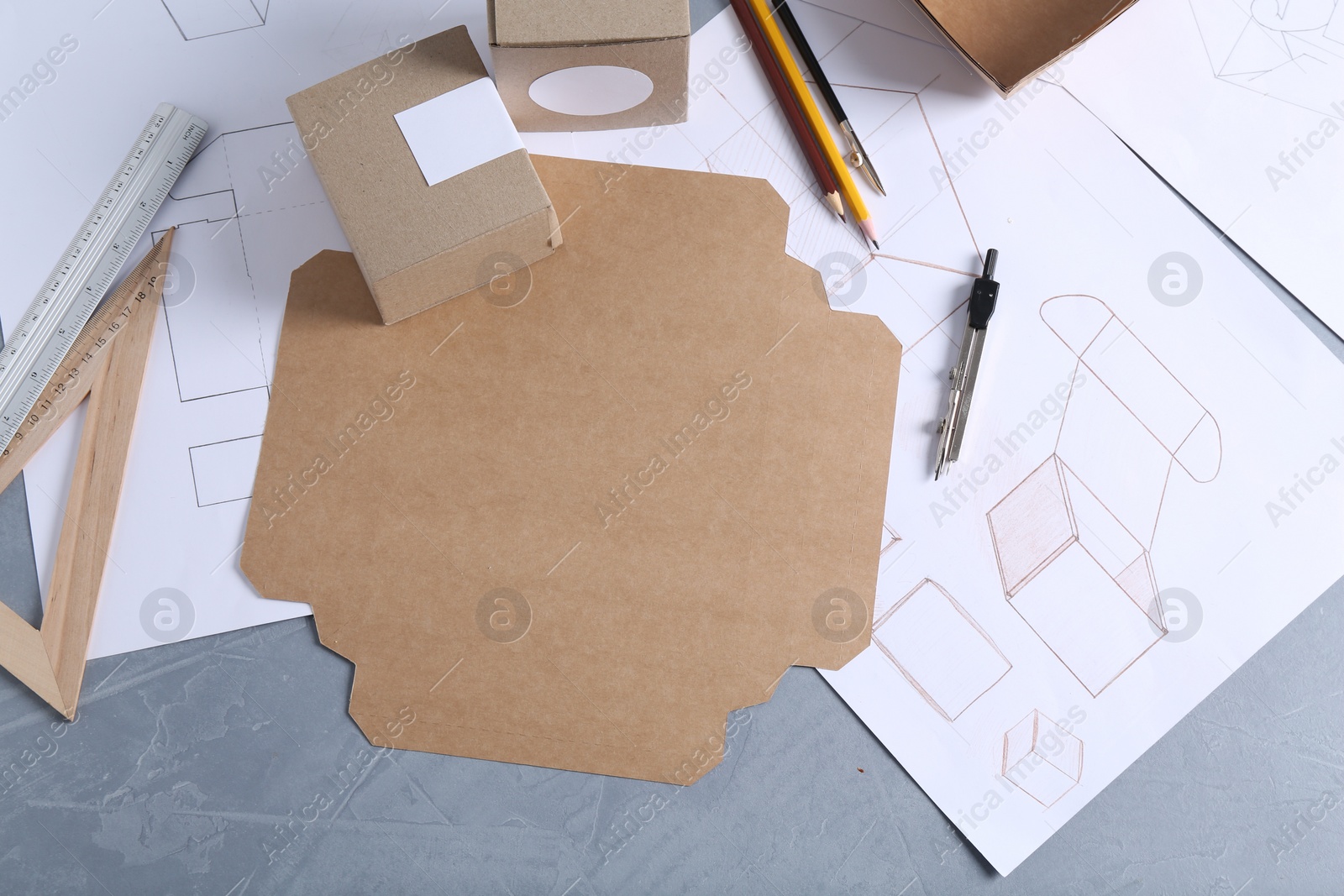 Photo of Creating packaging design. Drawings, boxes and stationery on blue textured table, flat lay