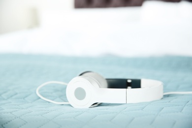 Photo of Stylish headphones on bed. Space for text