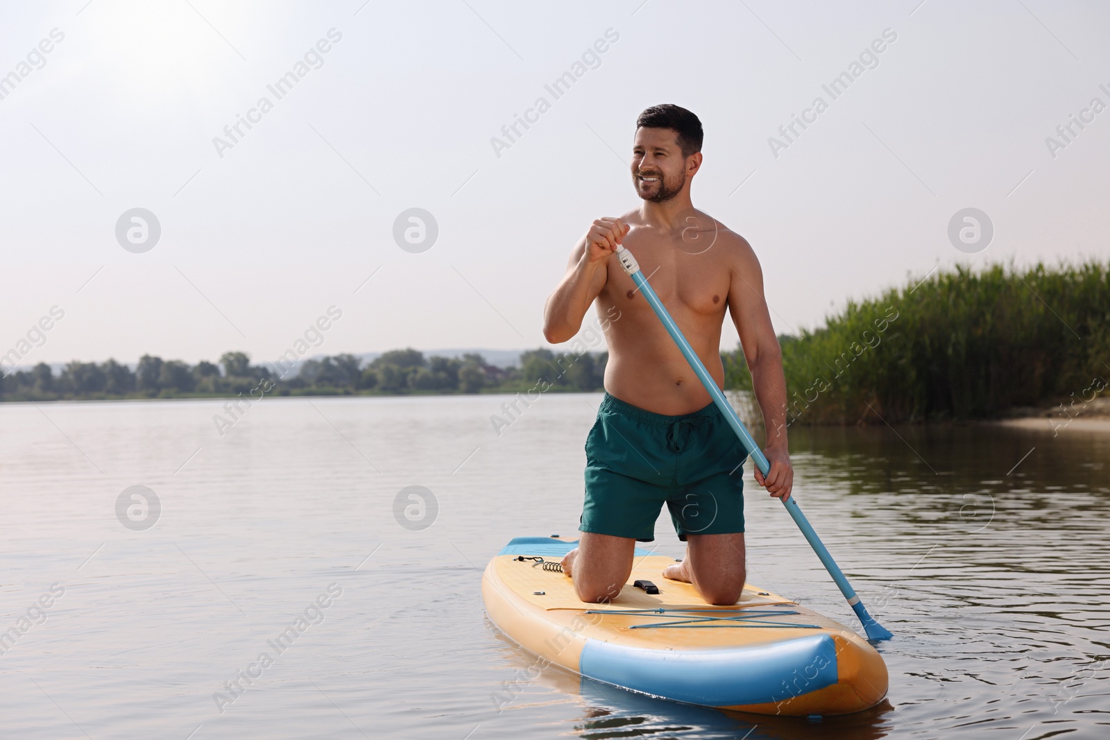 Photo of Man paddle boarding on SUP board in sea, space for text